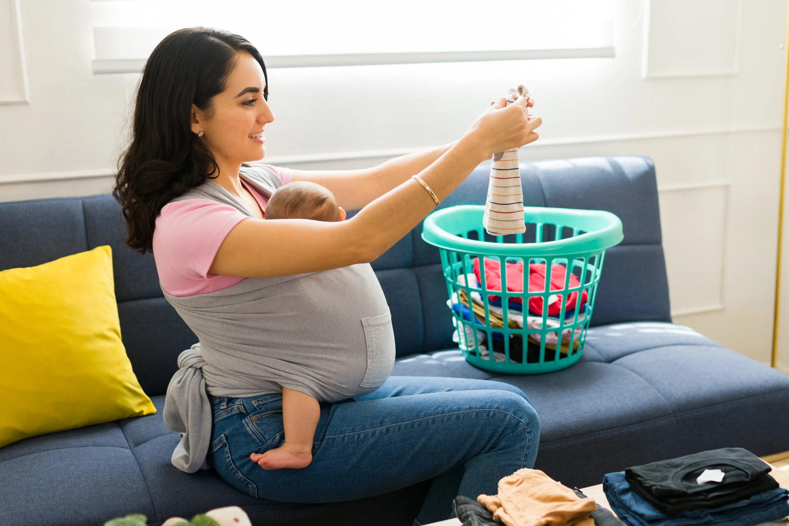 mom wearing baby doing laundry